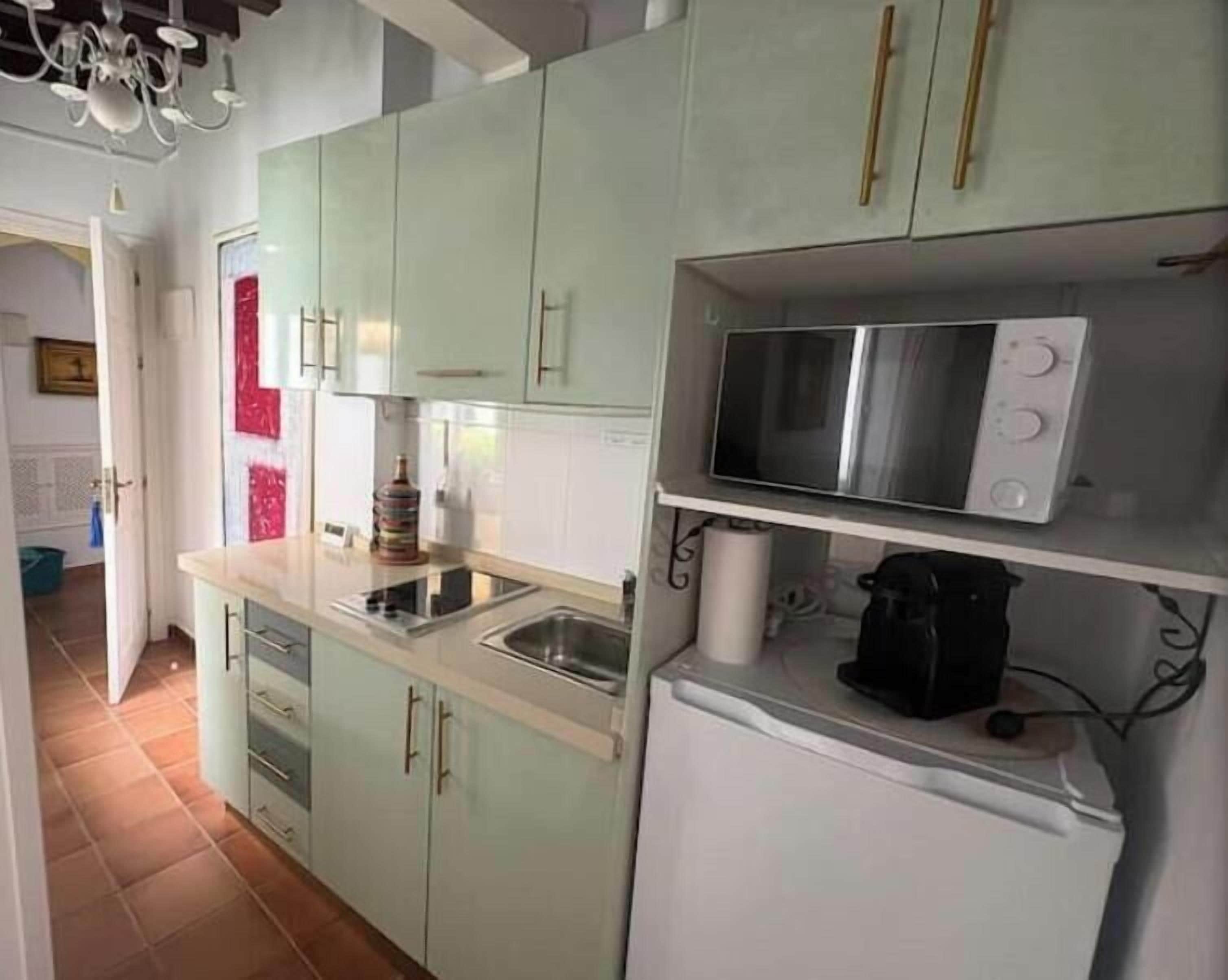 A kitchen with white cabinets, a microwave, and a refrigerator.