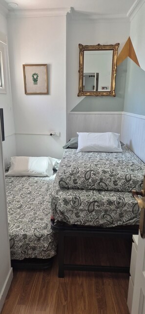 Ein Schlafzimmer mit zwei Betten, einem Spiegel und einem gerahmten Bild an der Wand.