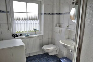 Een badkamer met toilet, wastafel en raam.