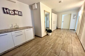 Um corredor com piso de madeira, armários brancos, uma placa com a palavra 'HOME' e um espelho.