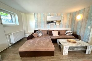 Ein gemütliches Wohnzimmer mit einem Ecksofa, einem Couchtisch und einem Gemälde an der Wand.