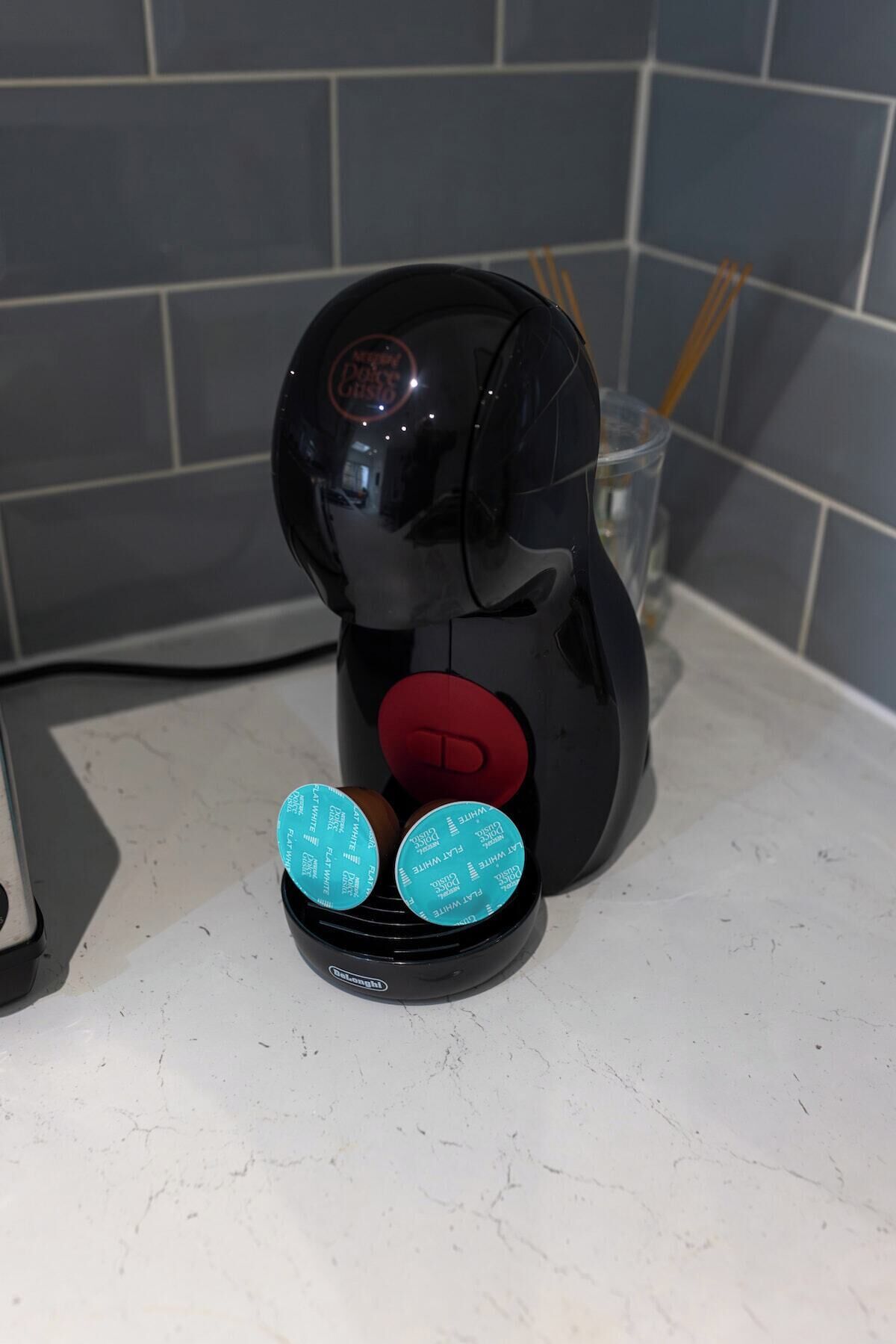 En kaffemaskine med to kaffekapsler på en bordplade.