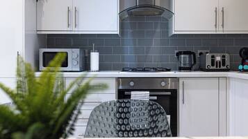 Cozinha moderna com armários brancos, micro-ondas, torradeira e cafeteira.