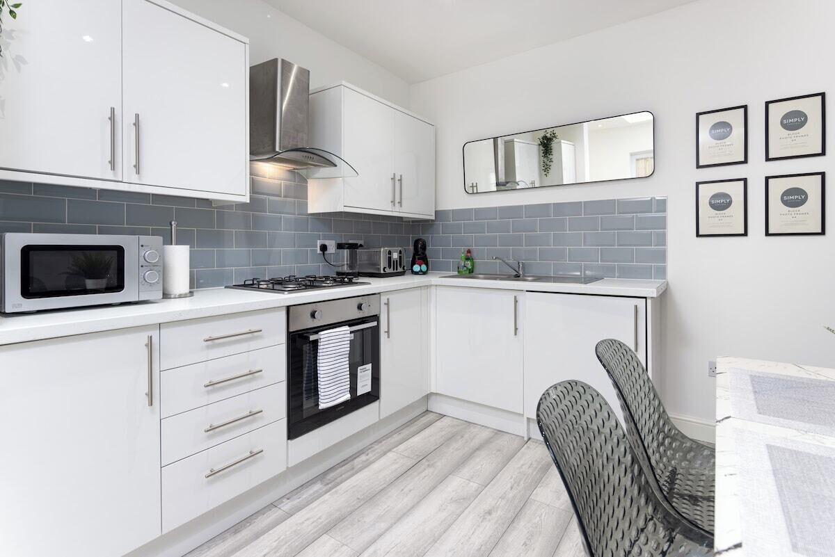 A modern kitchen with white cabinets, a microwave, stove, and a sink.