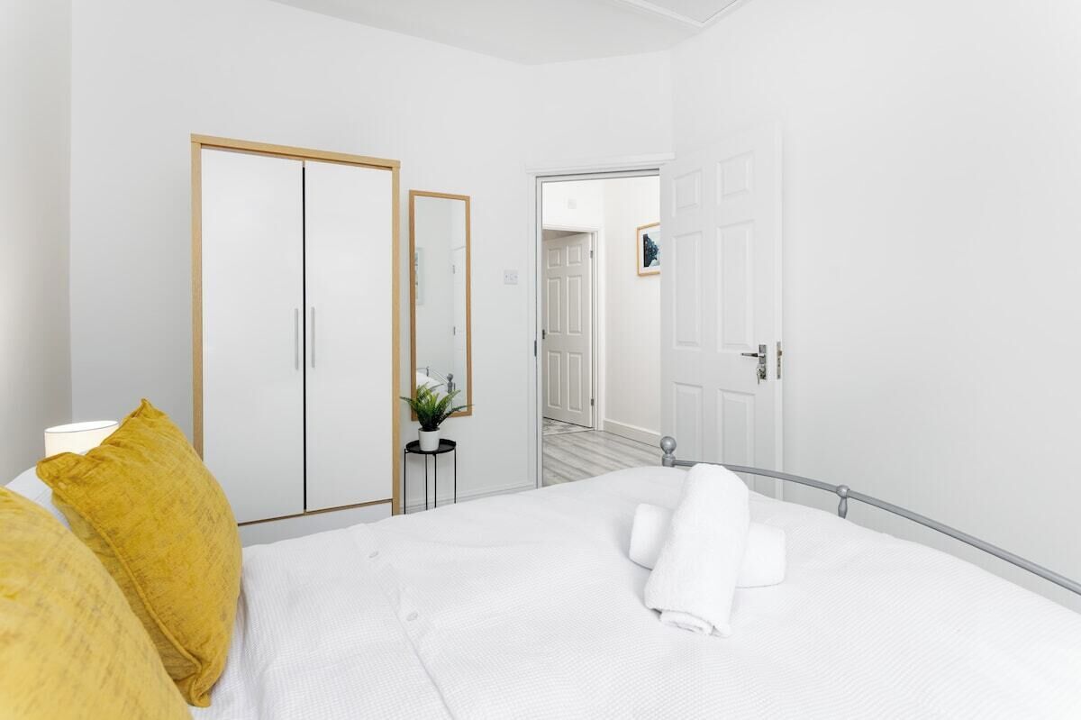 A hotel room with a bed, a wardrobe, a mirror, and a door leading to another room.