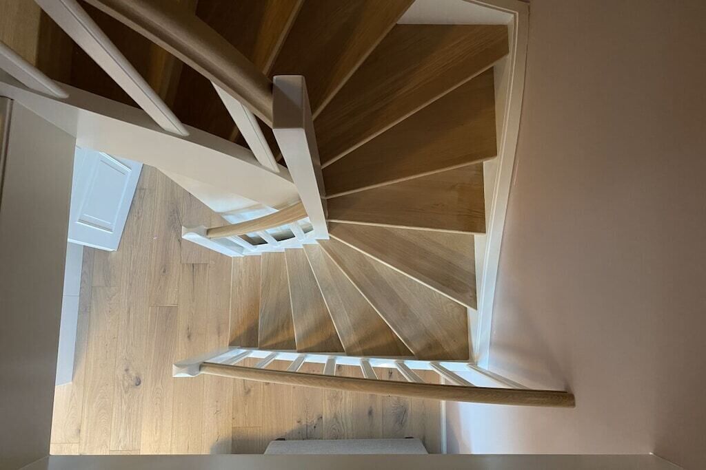 A spiral staircase with wooden steps and white railings.
