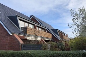 Ett modernt hus med ett sluttande tak, en fasad av tegel och en träaltan.