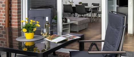 A modern living room with a glass table, a sofa, and a dining area with chairs and a table.