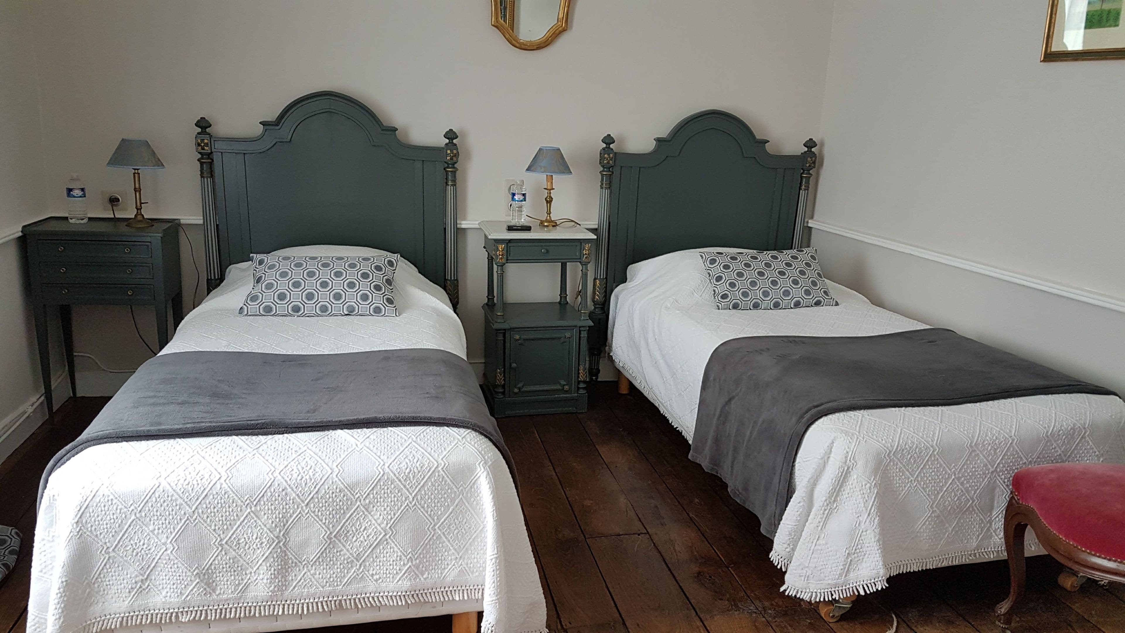 Una habitación con dos camas individuales, cada una con un cojín estampado y una mesita de noche con lámpara.