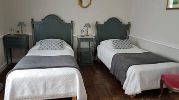 Une chambre avec deux lits simples, chacun agrémenté d’un coussin à motifs et d’une table de chevet avec une lampe.