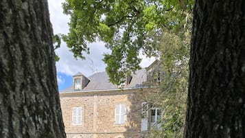 Un bâtiment en pierre doté de fenêtres en arc de cercle et d’un jardin magnifiquement entretenu.