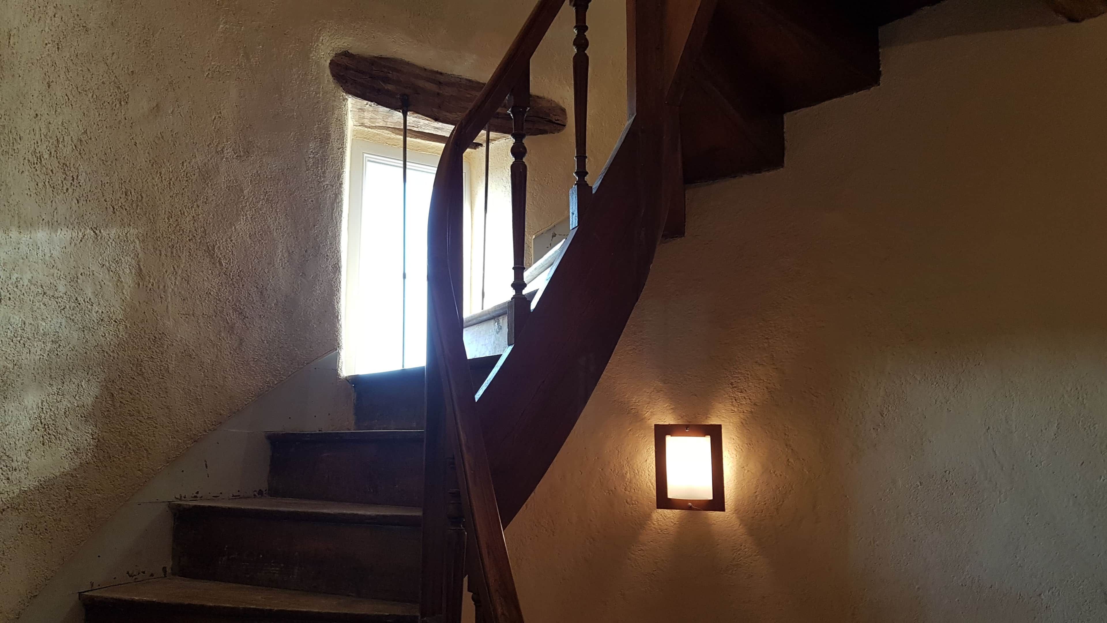 A wooden staircase with a handrail leading to a landing.