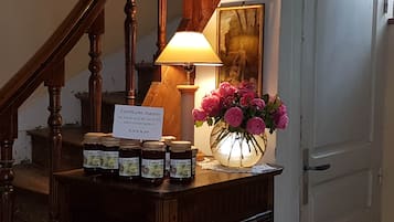 A wooden counter with jars of jam, a sign indicating the price, a vase of flowers, and a lamp.