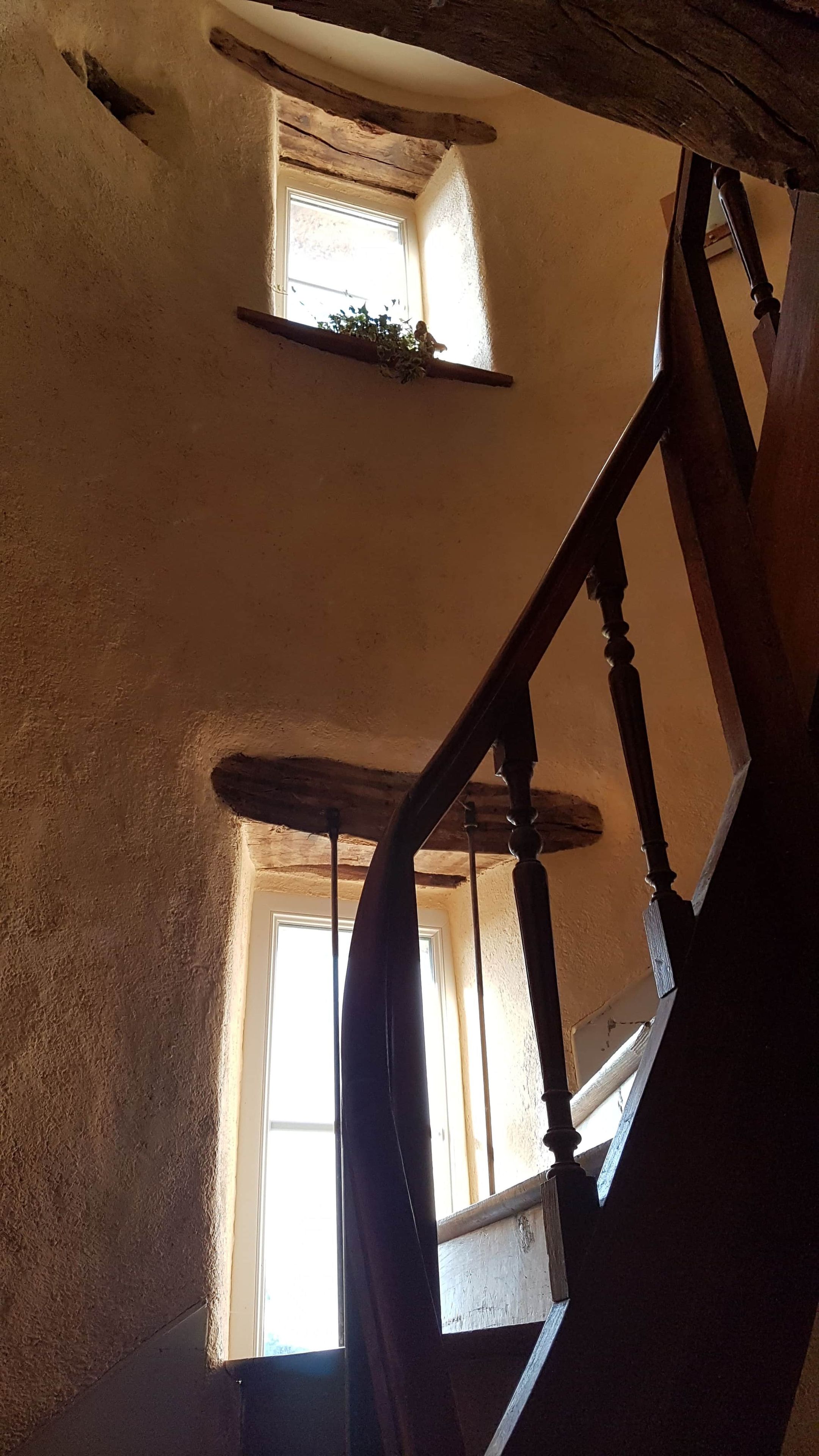 Una escalera con balaustres de madera y una pared con textura.
