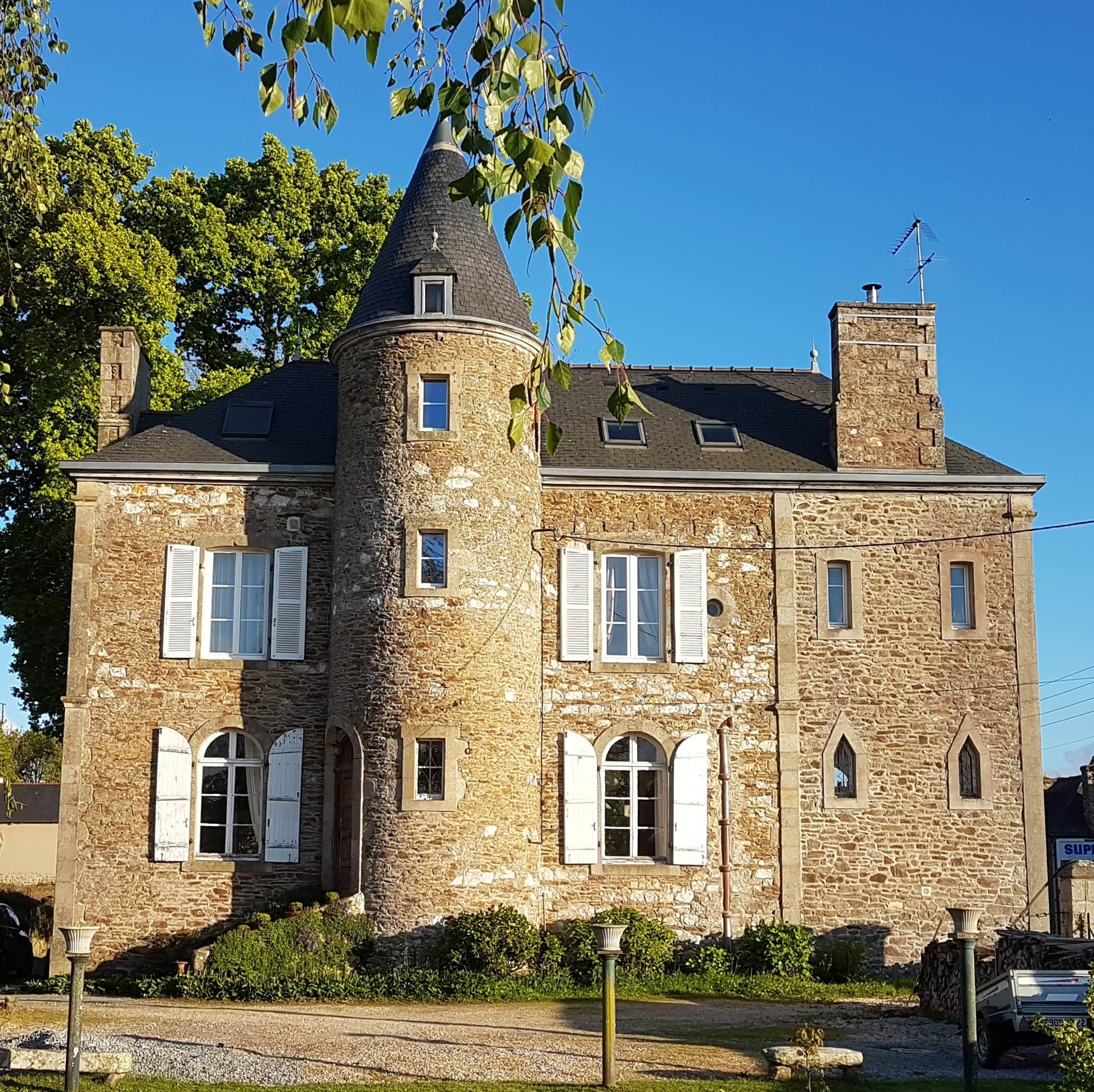 Un edificio de piedra con una torre, varias ventanas y una chimenea.