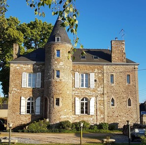 Un edificio de piedra con una torre, varias ventanas y una chimenea.