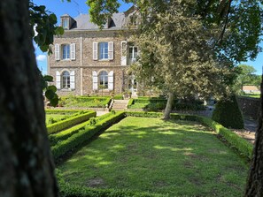 Ein Gebäude aus Stein mit Bogenfenstern und einem gepflegten Garten.
