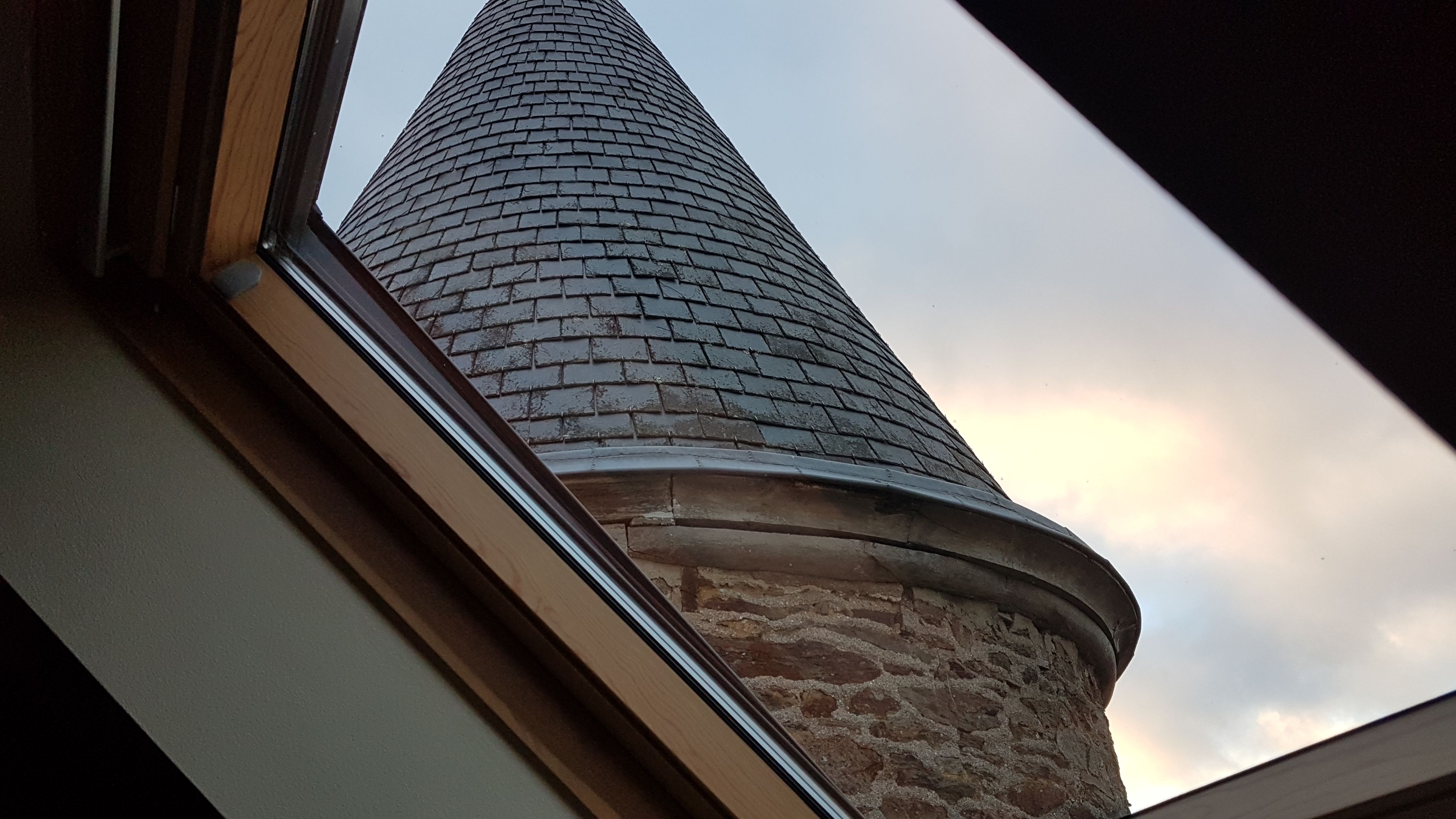 A brick chimney with a rounded top, viewed from a window.