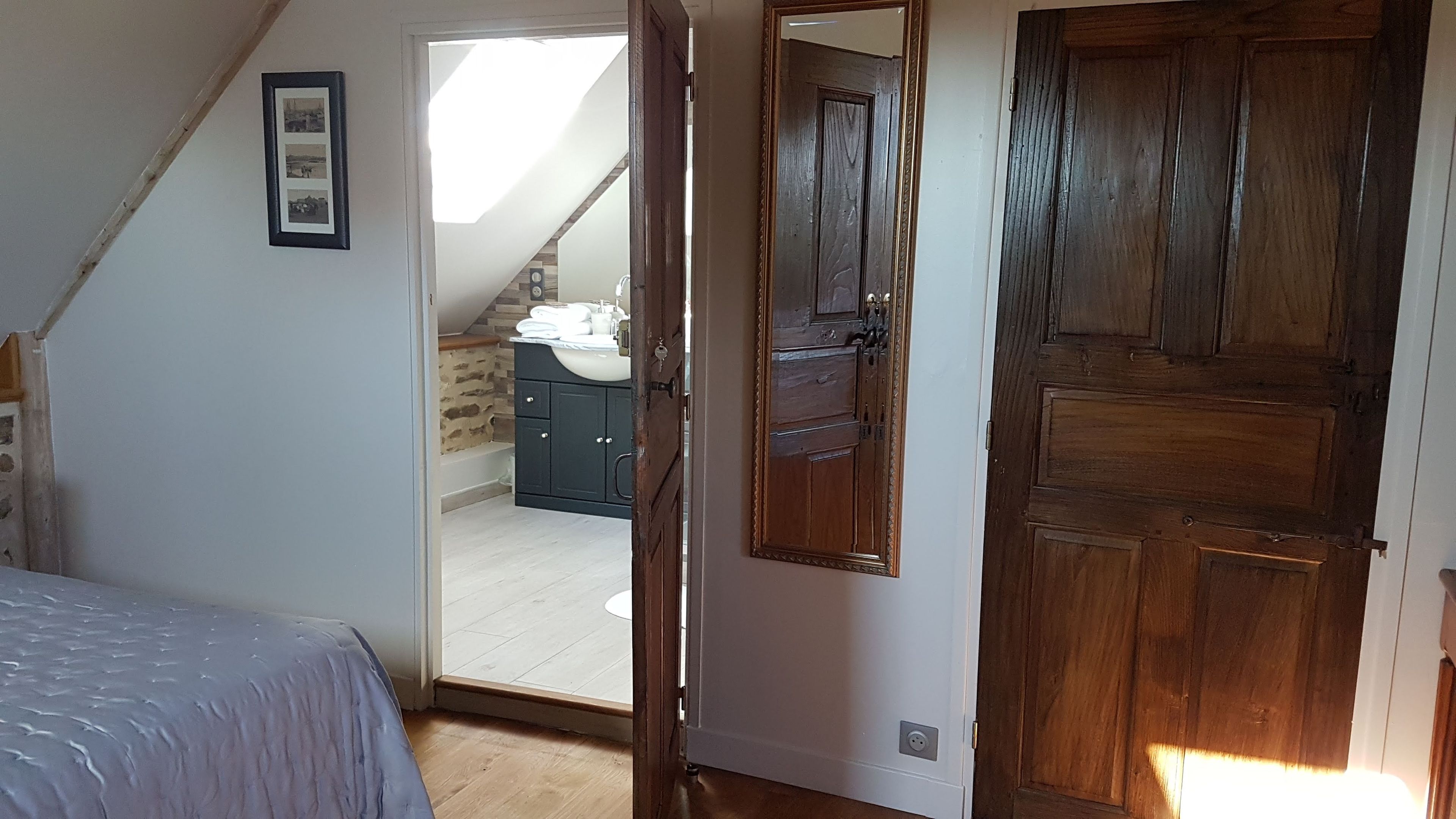 Ein Schlafzimmer mit einem Bett, einer Holztür und einer offenen Tür zu einem Badezimmer.