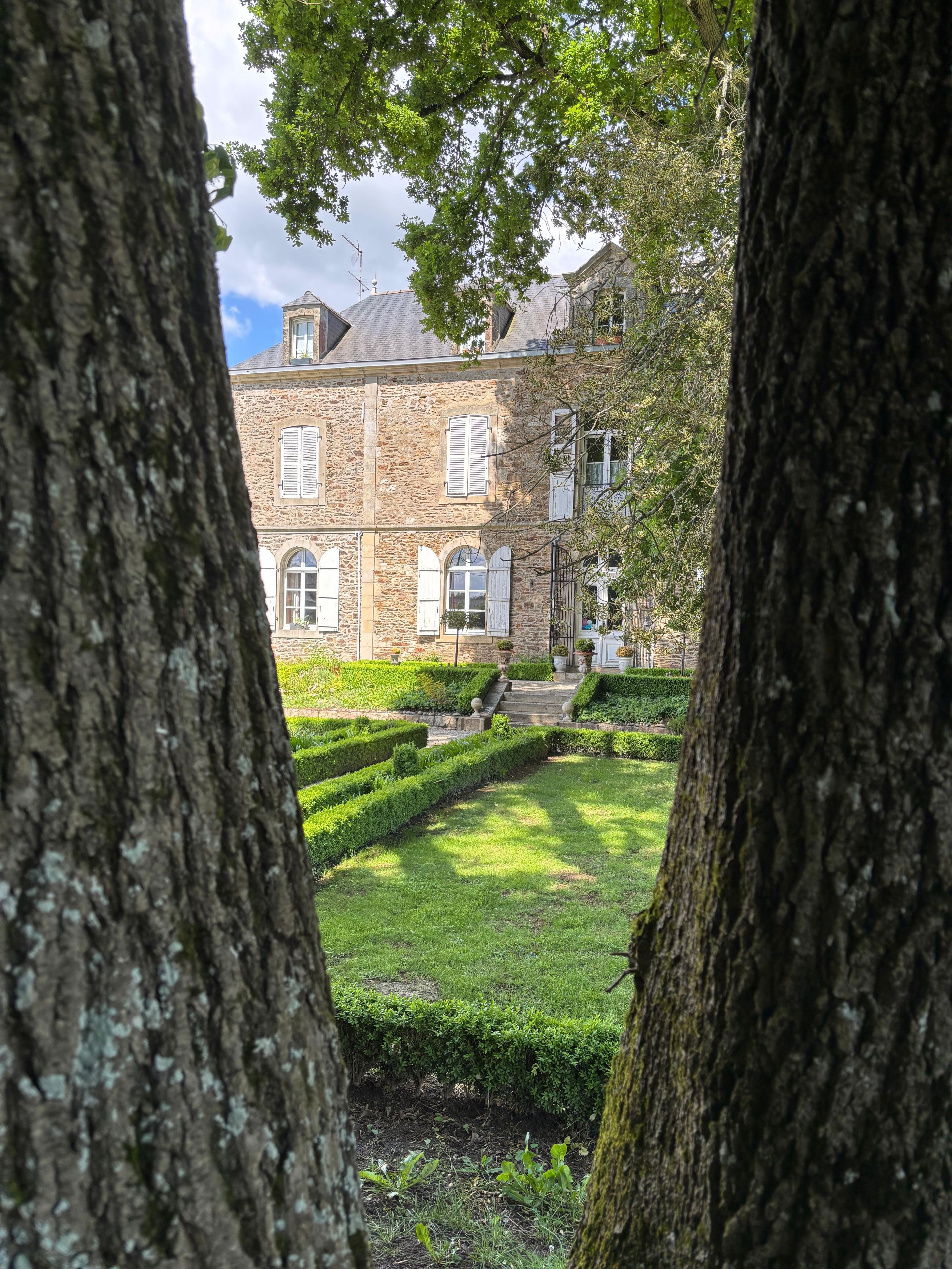 A stone building with arched windows and a well-maintained garden.