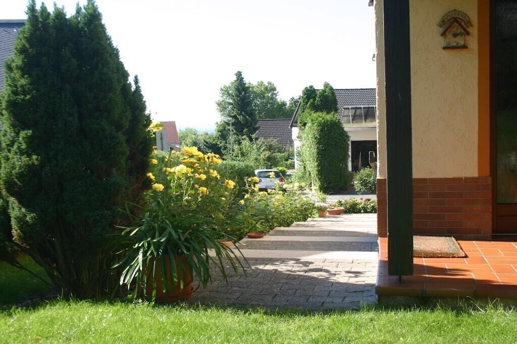 A pathway leading to a building with a brick facade and a small garden with yellow flowers.