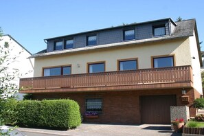 A two-story residential building with a balcony, a garage, and a well-maintained hedge. - Holiday apartment with 2 bedrooms (Rüdesheim am Rhein)