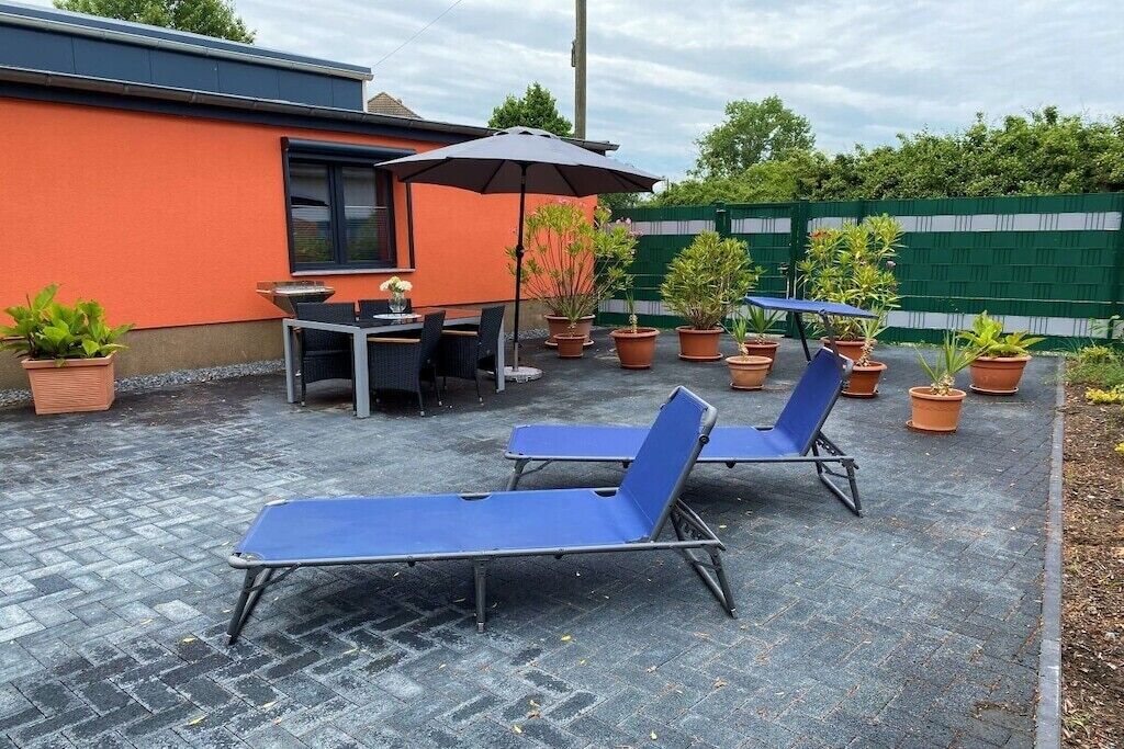 Area patio con poltrone, tavolo e piante in vaso.