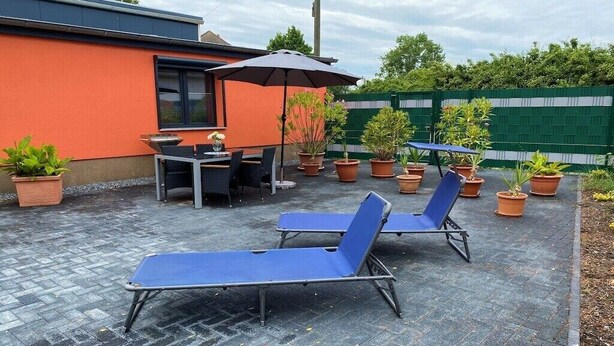 A patio area with lounge chairs, a table, and potted plants. - Holiday home in Zachow with swimming pool (Zachow)