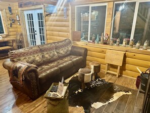 A log cabin interior with a sofa, a coffee table, a rug, and various decorative items. - A Custom-Built Swiss-Style Luxury Mountain Retreat - Lower Level 2 BR Unit (Mount Jackson)