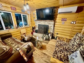 A cozy cabin interior with a fireplace, wooden walls, and a bar area. - A Custom-Built Swiss-Style Luxury Mountain Retreat - Lower Level 2 BR Unit (Mount Jackson)