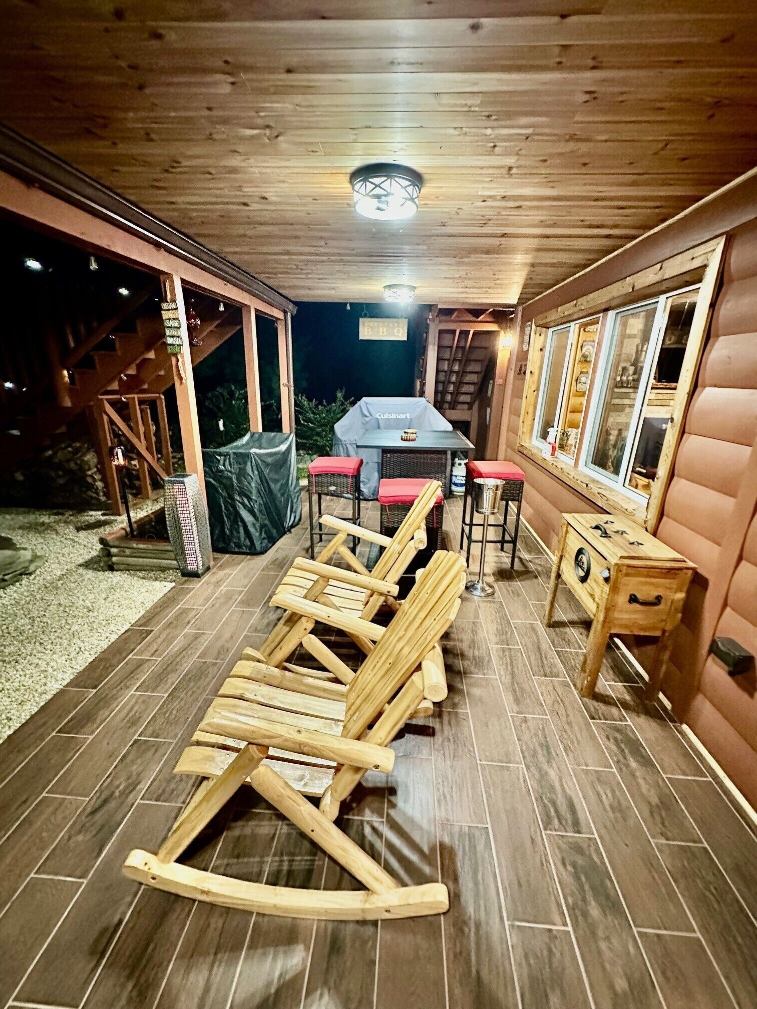 Um deck de madeira com área de refeições, assentos externos e churrasqueira.