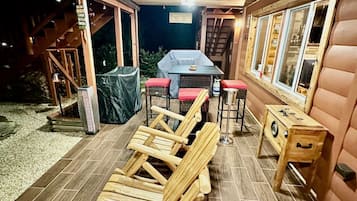 Um deck de madeira com área de refeições, assentos externos e churrasqueira.