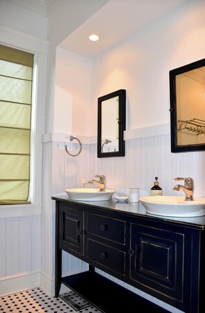 Une salle de bain avec deux lavabos, un miroir et une fenêtre avec des stores.