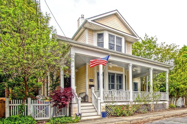 Une maison à deux étages avec un porche et un drapeau.