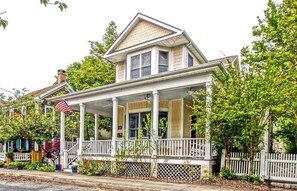 Une maison à deux étages avec un porche et une clôture en piquets.