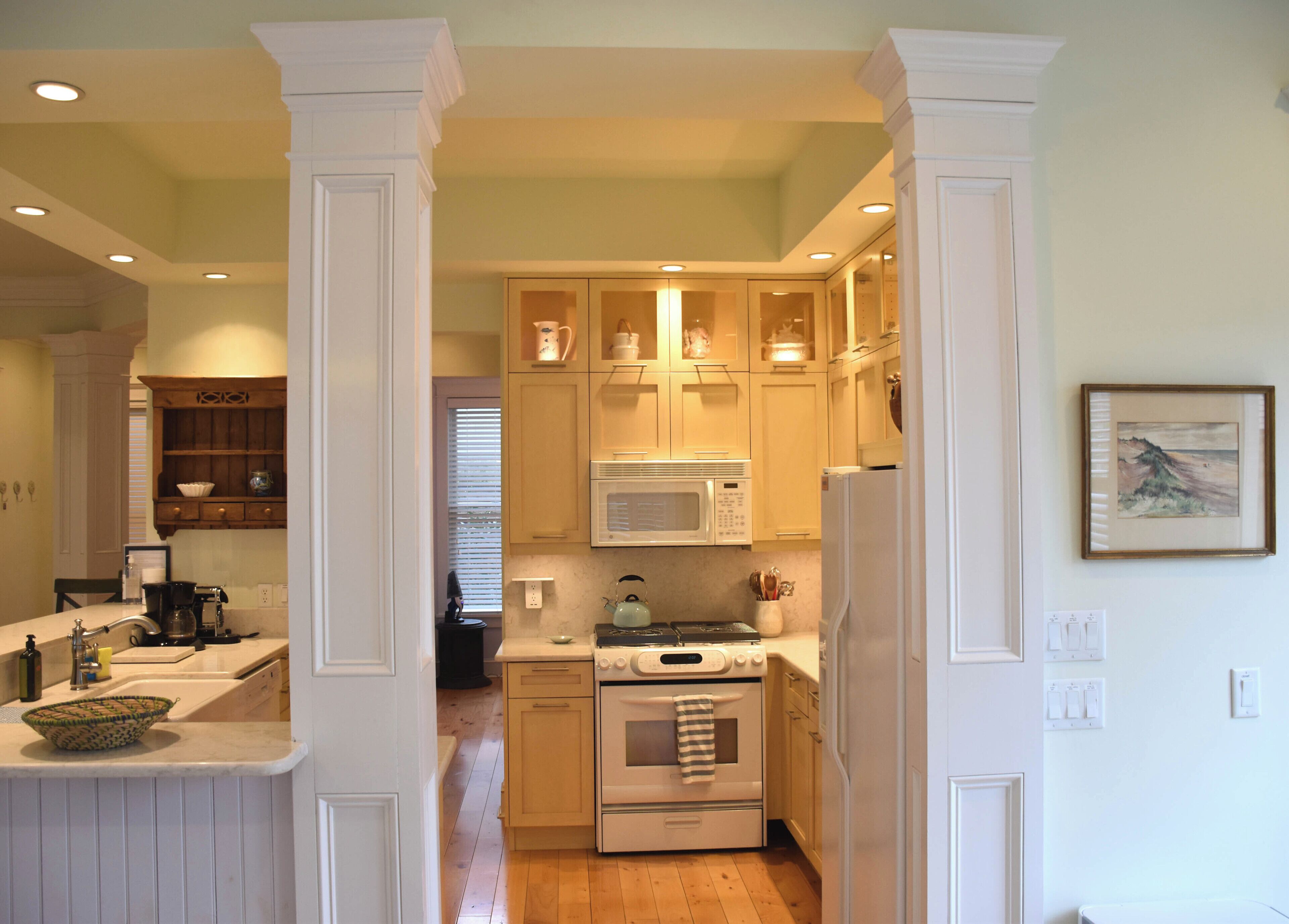 A kitchen with white cabinetry, a microwave, an oven, and a sink.