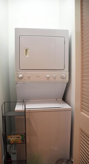 A compact, white, wall-mounted washer and dryer unit with control knobs and a small storage compartment.