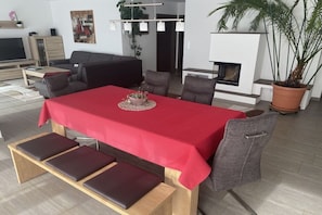 Een moderne woonkamer met een eethoek, een open haard en een televisie.