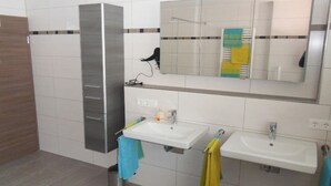 Un baño con dos lavamanos, un espejo y un perchero para toallas.