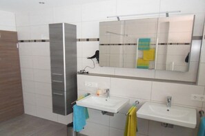 Een badkamer met twee wasbakken, een spiegel en een handdoekhouder.