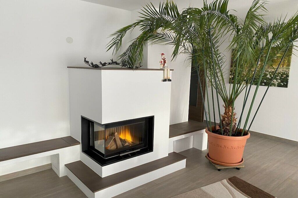 A modern fireplace with a flat-screen TV, a potted plant, and a minimalist design.