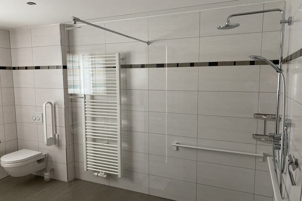 Ein modernes Badezimmer mit Dusche, Toilette und Handtuchhalter.