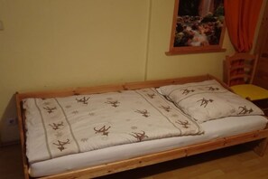 A single bed with a patterned bedspread, a wooden headboard, and a window with a curtain. - Holiday apartment in Suhl with swimming pool (Suhl)