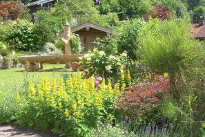 A garden with a wooden structure, a variety of plants, and a fence. - Holiday apartment with 1 bedroom (Schönau am Königssee)