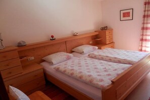 A bedroom with two wooden beds, a nightstand, a dresser, and a small shelf with decorative items. - Holiday apartment with 1 bedroom (Schönau am Königssee)