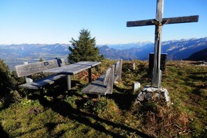 A wooden bench and a cross in a natural setting with mountains in the background. - Holiday apartment with 1 bedroom (Schönau am Königssee)
