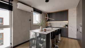 A modern kitchen with a central island, built-in appliances, and a large window. - Nowa Letnica - Gdańsk Panoramic View  (Gdańsk)