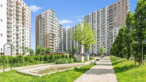 A residential area with high-rise apartment buildings, a paved walkway, and a small water feature.