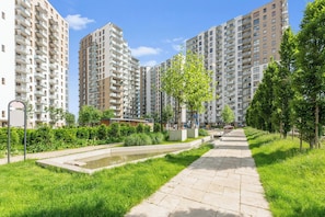 A residential area with high-rise apartment buildings, a paved walkway, and a small water feature. - Nowa Letnica - Gdańsk Panoramic View  (Gdańsk)