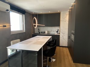 A modern kitchen with a marble backsplash, a central island with chairs, and a pendant light. - Nowa Letnica - Gdańsk Panoramic View  (Gdańsk)